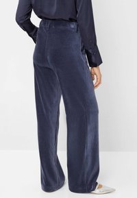 Navy corduroy wijde broek met een gladde textuur, voorzien van een hoge taille en subtiele stikdetails, gecombineerd met zilveren puntige schoenen.