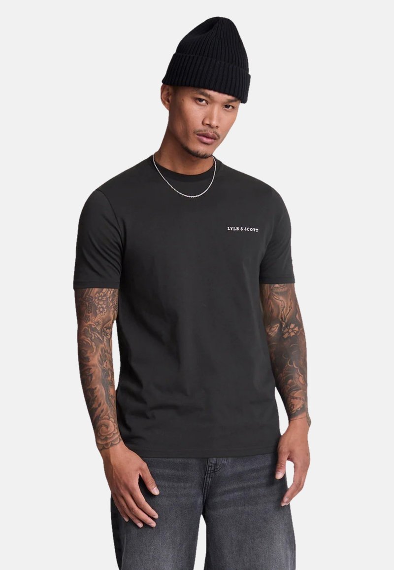 Tricou din bumbac negru cu mâneci scurte și guler rotund, având un mic logo alb pe partea stângă a pieptului. Asortat cu blugi din denim închis.