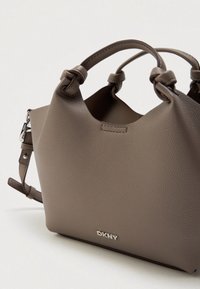 Ταμπά τσάντα από υφασμένο δέρμα με κόμπους, αποσπώμενο λουράκι και ασημένιο λογότυπο DKNY μπροστά.