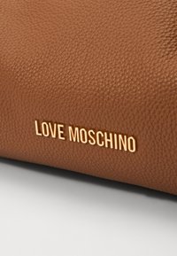 Brown textured leather bag featuring a gold "LOVE MOSCHINO" logo accent. The surface shows a pebbled pattern for added detail.
