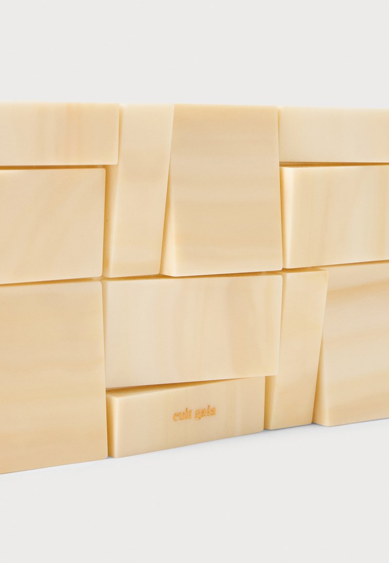 Art mural en résine couleur crème avec des formes rectangulaires irrégulières, présentant une texture lisse et un subtil veinage. Détail gravé "cult gaia".