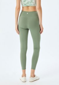 Lichtgroene leggings van rekbaar materiaal, met een hoge tailleband, gladde textuur en enkel lengte.