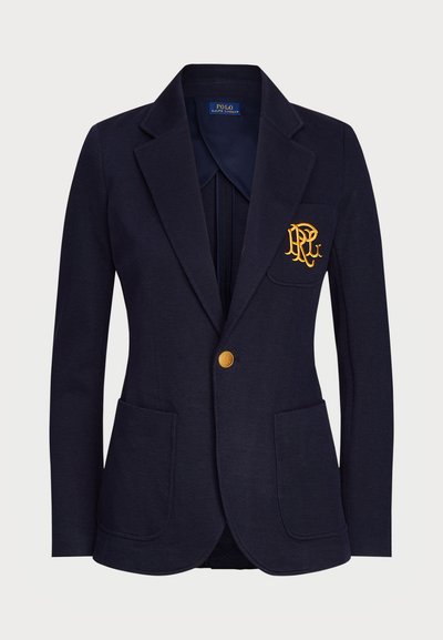 Granatowy blezer wykonany z teksturowanej tkaniny, z złotym guzikiem oraz haftowanym logo na kieszeni piersiowej. Zawiera dwie kieszenie z przodu.