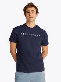 Marineblå bomulls T-skjorte med "TOMMY JEANS"-logo i hvitt. Korte ermer, rund hals og en avslappet passform. Minimalistisk design.