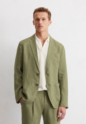 Light green linen blazer with two front pockets, two buttons, and a textured white polo shirt underneath. Tailored fit, casual design.