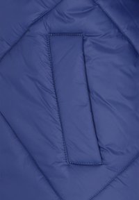 Blaues Puffermantel-Gewebe mit einem gesteppten Design. Glatte Textur mit einer rechteckigen Tasche und sichtbaren Nähten entlang der Kanten.