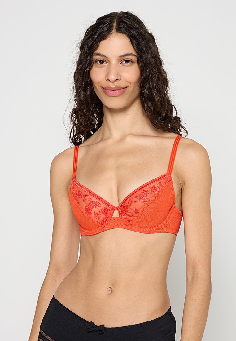 Rode beha met doorschijnende geborduurde overlay, met driehoekige cups en een klein sleutelgatdetail. Dunne verstelbare bandjes en een gladde textuur.