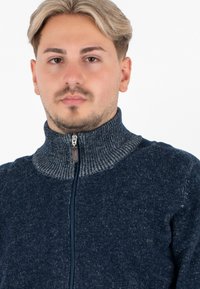 Maglione zip-up blu navy con colletto alto, texture a costine e dettagli grigi sul collo. Presenta una cerniera frontale e un materiale morbido.