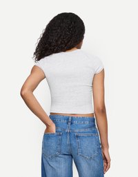 Gray, cropped t-shirt with short sleeves paired with high-waisted, light blue denim jeans featuring back pockets and a relaxed fit.