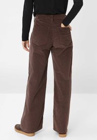 Braune Corduroy weit geschnittene Hosen mit einem elastischen Bund und zwei Gesäßtaschen, die eine weiche Textur und einen lockeren Sitz aufweisen.