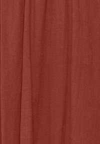 Tissu de couleur rouille avec des plis verticaux doux et une surface légèrement texturée.