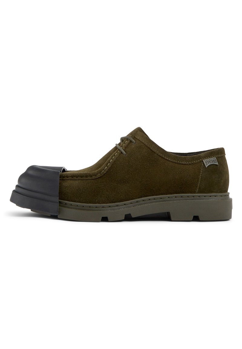 Scarpa in suede verde con una punta in gomma nera curvata, dettagli cuciti e una suola testurizzata con battistrada pronunciato per una maggiore aderenza.