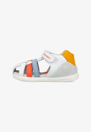 Sandalia blanca con detalles en naranja, azul y amarillo, correa ajustable y punta abierta, diseñada para niños.