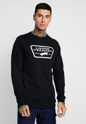 Sudadera negra de manga larga con un logotipo blanco de Vans en el frente, con puños acanalados y cuello redondo. Tejido suave, corte casual.