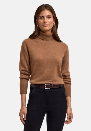 Maglione a collo alto marrone in tessuto morbido, con un design aderente e polsini a costine, abbinato a pantaloni neri e una cintura marrone.