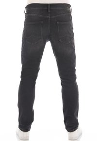Jeans de mezclilla negra con corte ajustado, que cuentan con cinco bolsillos, una cintura de altura media y una sutil textura deslavada. La vista trasera muestra detalles de bolsillos cosidos.