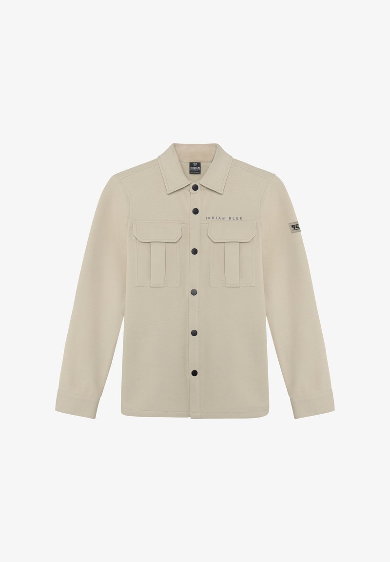 Veste beige à manches longues, devant boutonné, avec deux poches poitrine et une étiquette de marque. Présente des boutons foncés et des poches plaquées texturées.