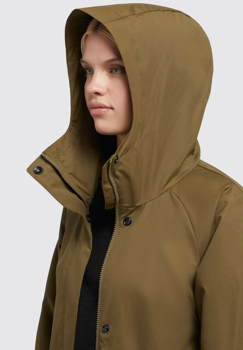 Braune Kapuzenjacke mit einer glatten, matten Oberfläche, ausgestattet mit Druckknopf- und Reißverschluss, detaillierten Nähten und einem lockeren Schnitt.