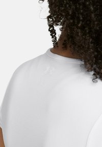 Witte sportshirt gemaakt van gladde stof, met een ronde hals en een subtiele logodetail op de rug nabij de hals.