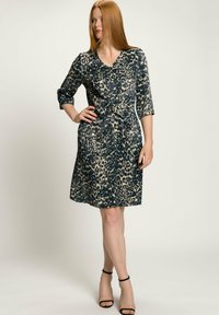 Leopardenmusterkleid in Dunkelblau und Beige, knielang, mit V-Ausschnitt, Dreiviertelärmeln und einem geknoteten Taillendetail. Glatte Stoffstruktur.