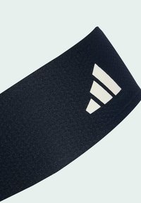 Cinta atlética negra hecha de material texturizado, que presenta un logotipo de tres rayas en blanco contrastante en un lado.