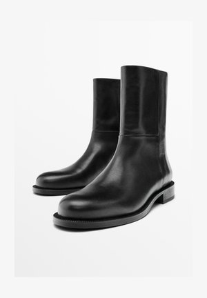 Schwarze Lederstiefeletten mit einem schlanken Design, runder Spitze und niedrigem Blockabsatz. Glatte Textur und minimalistische Silhouette.