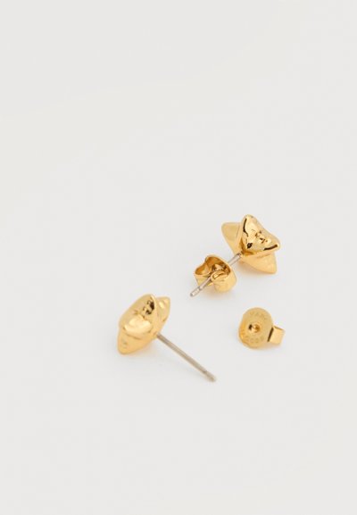 Goldene Ohrstecker in Sternform mit Metallstiften und Schmetterlingsverschlüssen auf weißer Oberfläche.