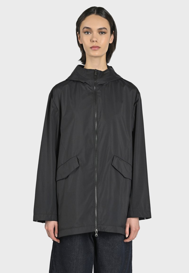 Giacca da pioggia nera, leggera, con cappuccio, cerniera frontale e due ampie tasche laterali. Tessuto liscio, vestibilità ampia e maniche lunghe.