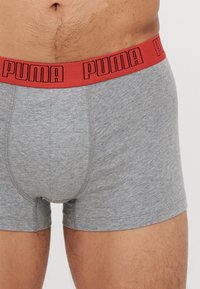 Szürke pamut boxer alsónadrág piros gumírozott derékkal, melyen fekete "PUMA" logó található. Simaság, testhez álló设计.