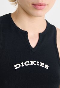 Zwarte geribbelde tanktop met een V-hals en een witte grafische logo "DICKIES" op de borst. Gestructureerde stof met een aansluitend ontwerp.