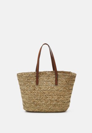 Sac de course en paille tissée avec des poignées en cuir brun clair. Forme arrondie avec un motif en chevron complexe sur toute la surface.