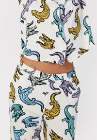 Krokodilmönstrad loungeklädesset i vitt, med färgglada reptilmönster i gult, blått och lila. Mjuk, lättviktig tyg.