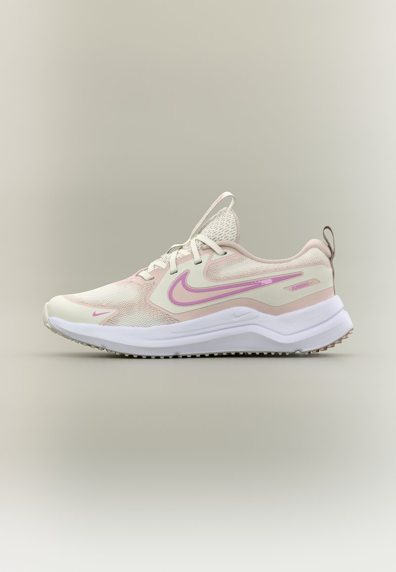 Ανοιχτό ροζ και λευκό αθλητικό παπούτσι Nike για τρέξιμο με ύφασμα από πλέγμα, μαλακή σόλα και δέσιμο με κορδόνια, εμφανιζόμενο από το πλάι σε ουδέτερο φόντο.