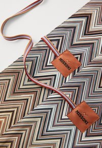 Missoni mønstrete stoff med et flerfarget sikksakk-design, med et brunt lærmerke. Inkluderer et stripete håndtak i dempede farger.