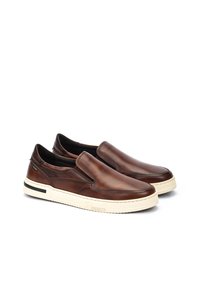 Bruine leren instapschoenen met een gladde afwerking, witte rubberen zool en subtiele zwarte accenten. Voorzien van elastische zij-invoegen voor eenvoudig aan- en uittrekken.