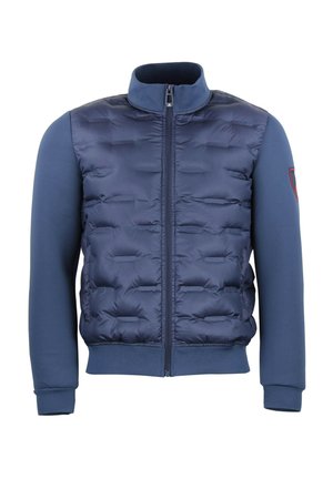 Veste matelassée marine avec fermeture éclair, présentant un devant matelassé, des manches longues lisses et des poignets côtelés. Comprend un petit détail de logo sur la manche.