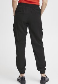 Zwarte cargobroek met een elastische tailleband, taps toelopende boorden, zijzakken en een gladde, lichte stoftextuur.