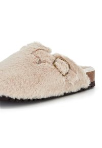 Chausson en fausse fourrure de couleur rose doux avec une surface texturée, doté d'une boucle sur le côté et d'une semelle flexible pour le confort.