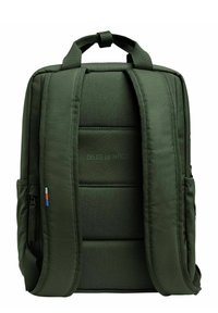 Zaino in tessuto verde con schienale imbottito, spallacci regolabili, due tasche laterali e un dettaglio testuale "CREATE AN IMPACT" sul retro.