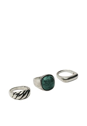 Three silver rings, one with twisted design, one with square turquoise stone, and one with a smooth angled band on white background.