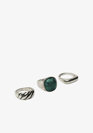 Three silver rings, one with twisted design, one with square turquoise stone, and one with a smooth angled band on white background.