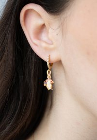 Guldörhänge med en färgglad kaninberlock som har på sig en rosa kappa och håller en korg. Har små glittrande detaljer på hängsmycket.