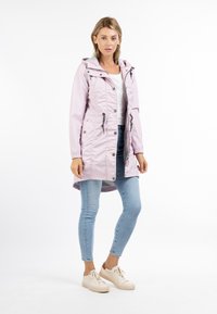 Giacca impermeabile rosa chiaro con cappuccio, lacci di stringa e chiusura a pressione, dotata di tasche laterali e una lunghezza del retro leggermente più lunga.