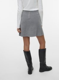 Szara rozkloszowana spódnica typu skater o gładkiej fakturze, z tylnym zamkiem i subtelnym przeszyciem, połączona z czarnymi skórzanymi butami za kolano.