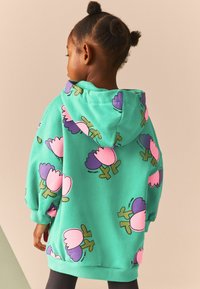 Sudură cu glugă verde, cu un model floral în roz și mov. Fabricată dintr-un material moale, cu o croială lejeră și tiv cu nervuri.