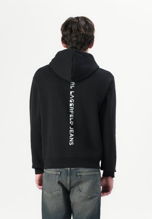 Sort hættejakke med et stort hvidt logo "Karl Lagerfeld Jeans" på midten af ryggen, med snor i hætten og ribbede manchetter.