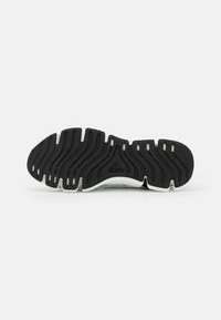 Semelle en caoutchouc noir avec un motif de bande de roulement en forme de vagues et une semelle intermédiaire blanche. Présente un logo Adidas en relief et une surface texturée pour une meilleure traction.