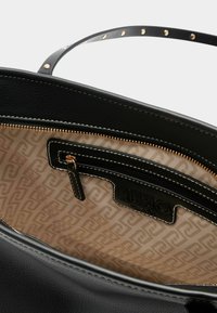 Fekete bőr kézitáska texturált külsővel, arany cipzáras záródással és mintás bézs béléssel, amelyen a márka logója látható. Belső cipzáras zsebbel.