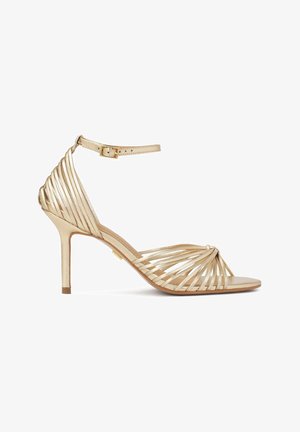 Sandale à talons hauts avec lanières, finition dorée métallique, dotée d'une bride de cheville, d'un bout ouvert et d'un design entrecroisé à l'avant.