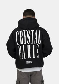 Felpa nera con cappuccio caratterizzata da un audace testo bianco "CRYSTAL PARIS" e "DEPT.75" sul retro. Presenta una vestibilità rilassata e una texture morbida.